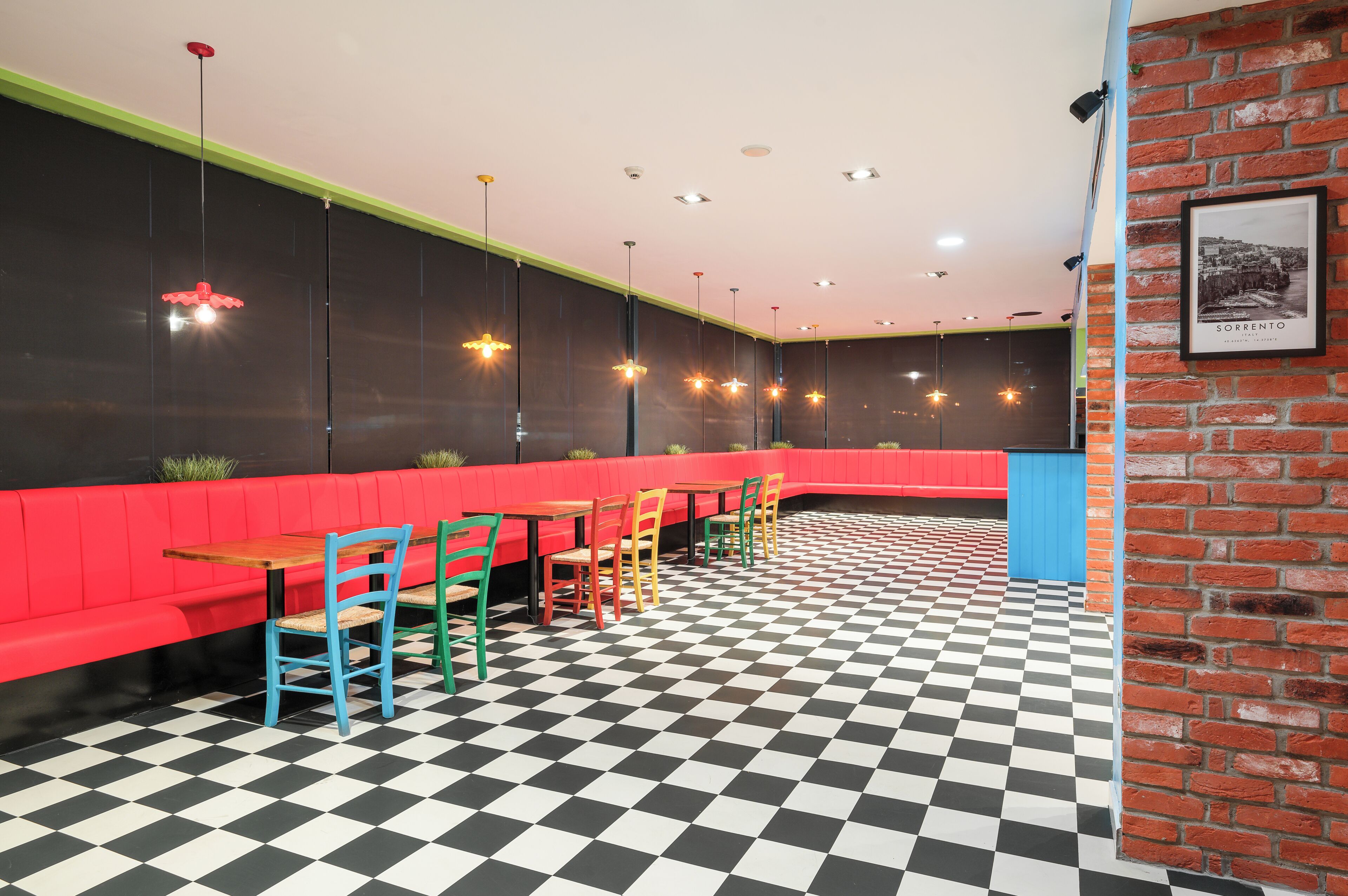 Un restaurant avec un sol à carreaux, des sièges rouges et des chaises colorées.