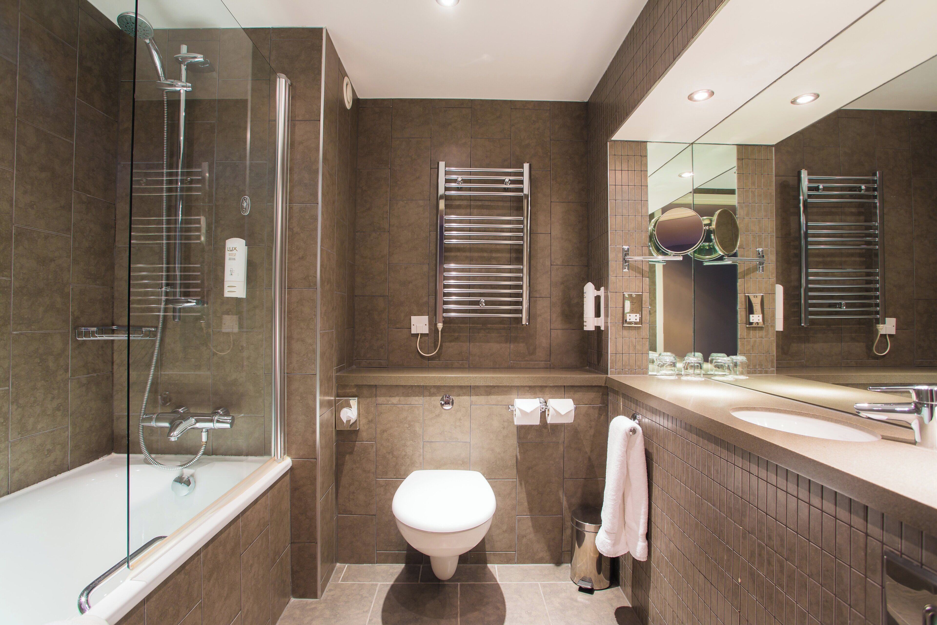 Een moderne badkamer met een douchecabine van glas, een toilet en een wastafel met spiegel.