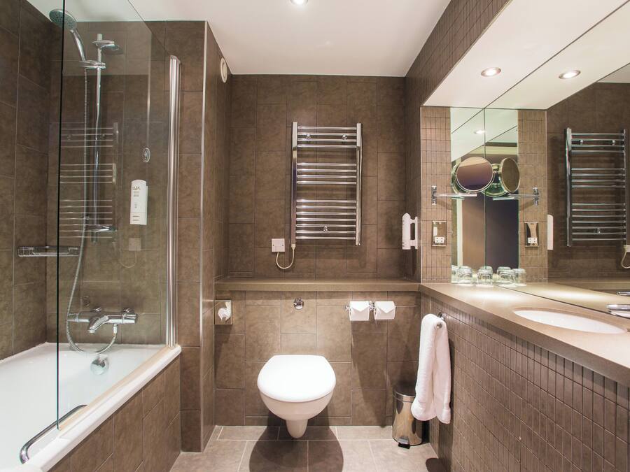 Een moderne badkamer met een douchecabine van glas, een toilet en een wastafel met spiegel.