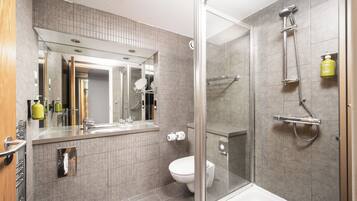 A modern bathroom with a glass-enclosed shower, a large mirror, and a toilet.