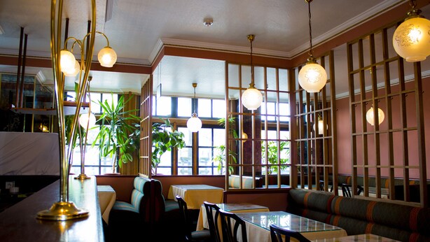 L’intérieur d’un restaurant, avec des banquettes, des tables et des lampes suspendues.