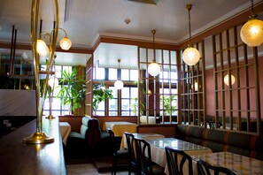 Ein Restaurantinnenraum mit Sitzecken, Tischen und hängenden Lampen.