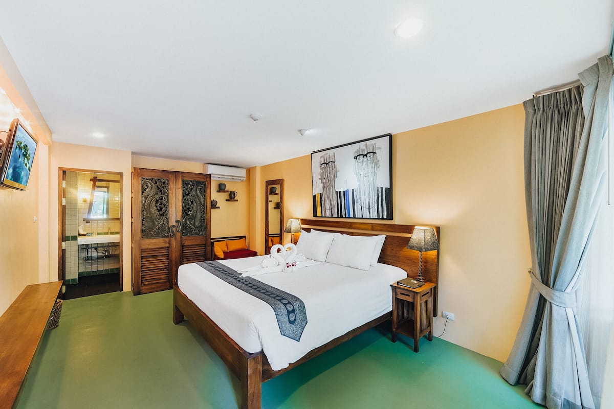A hotel room with a bed, bedside table, lamp, and a painting on the wall.