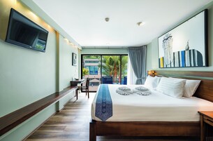 Habitación de hotel con una cama grande, un televisor de pantalla plana en la pared, un escritorio con una silla y vistas al exterior a través de un ventanal amplio.