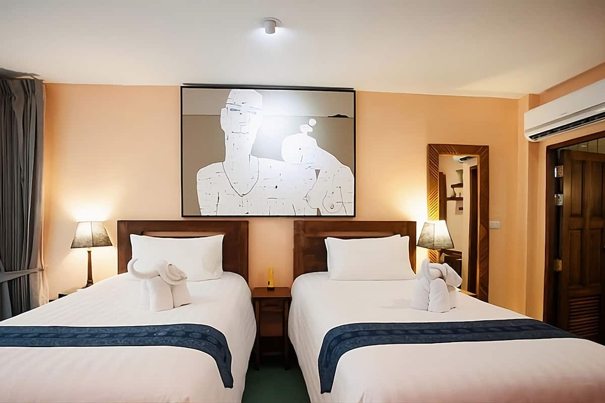 A hotel room with two beds, a large abstract painting on the wall, and a door with a mirror.