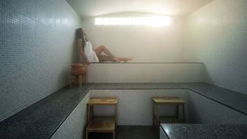 A spa room with a tiled wall, a bench, and a small wooden stool.