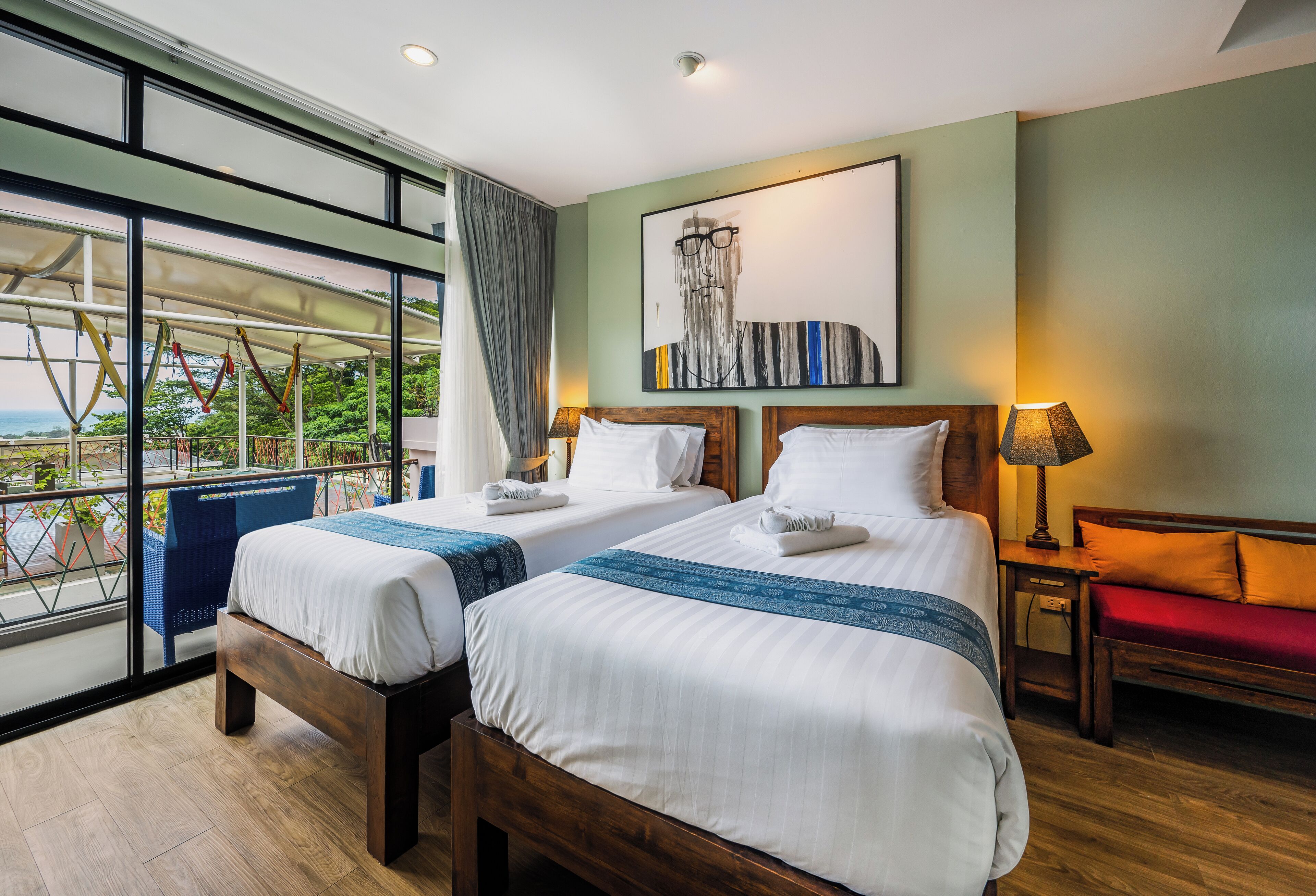 A hotel room with two beds, a balcony, a large window, and a painting on the wall.