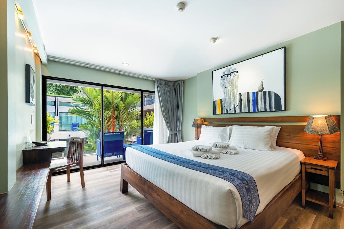 A modern hotel room with a large bed, a desk, and a view of the outdoors.