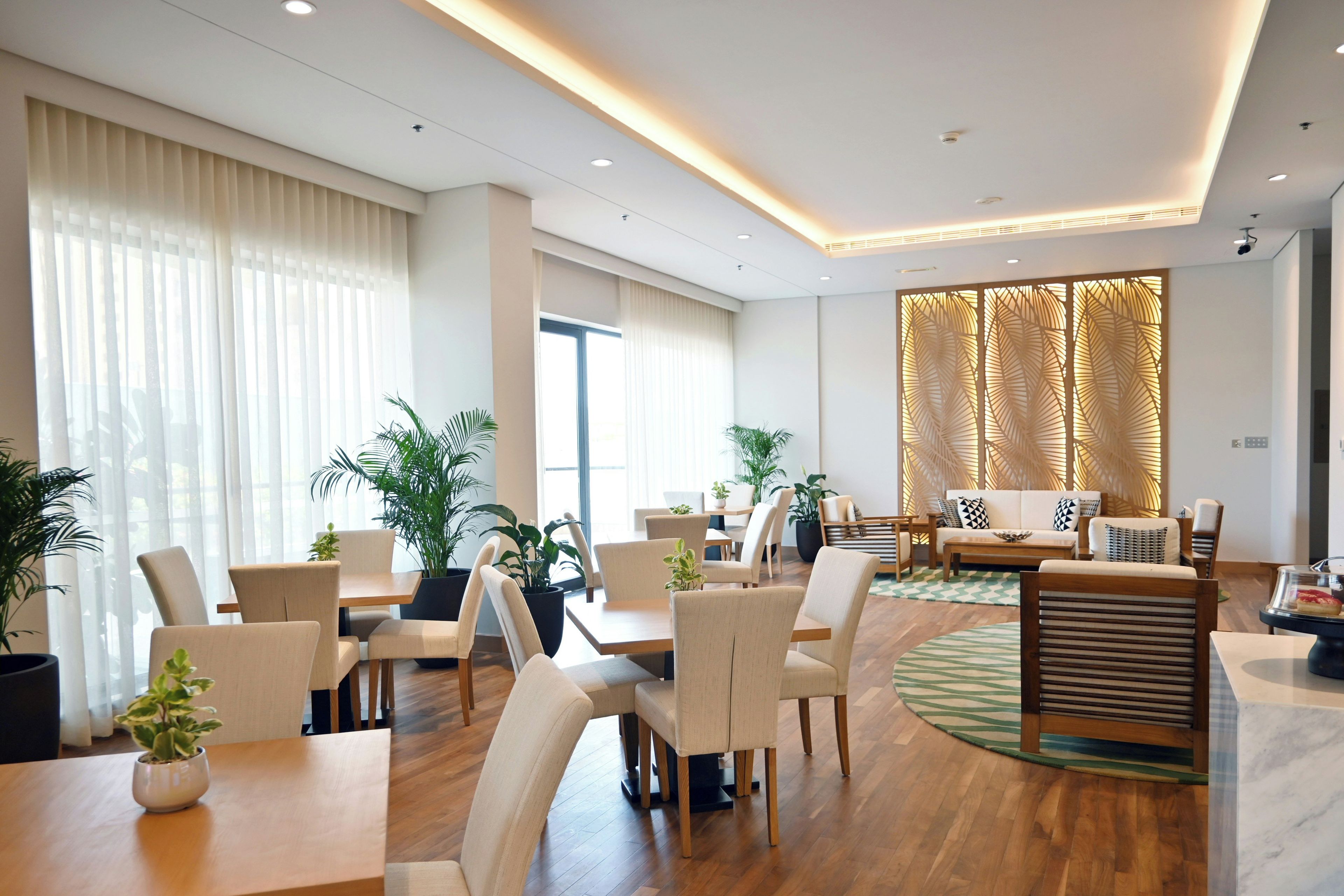 Een moderne hotel lobby met een receptiebalie, een zithoek en grote ramen.