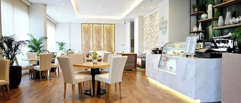 A modern coffee house interior with a wooden dining area, a counter with a coffee machine, and decorative plants.