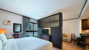 Une chambre d’hôtel avec un grand lit, une télévision, un bureau avec des chaises et une vue sur la ville.