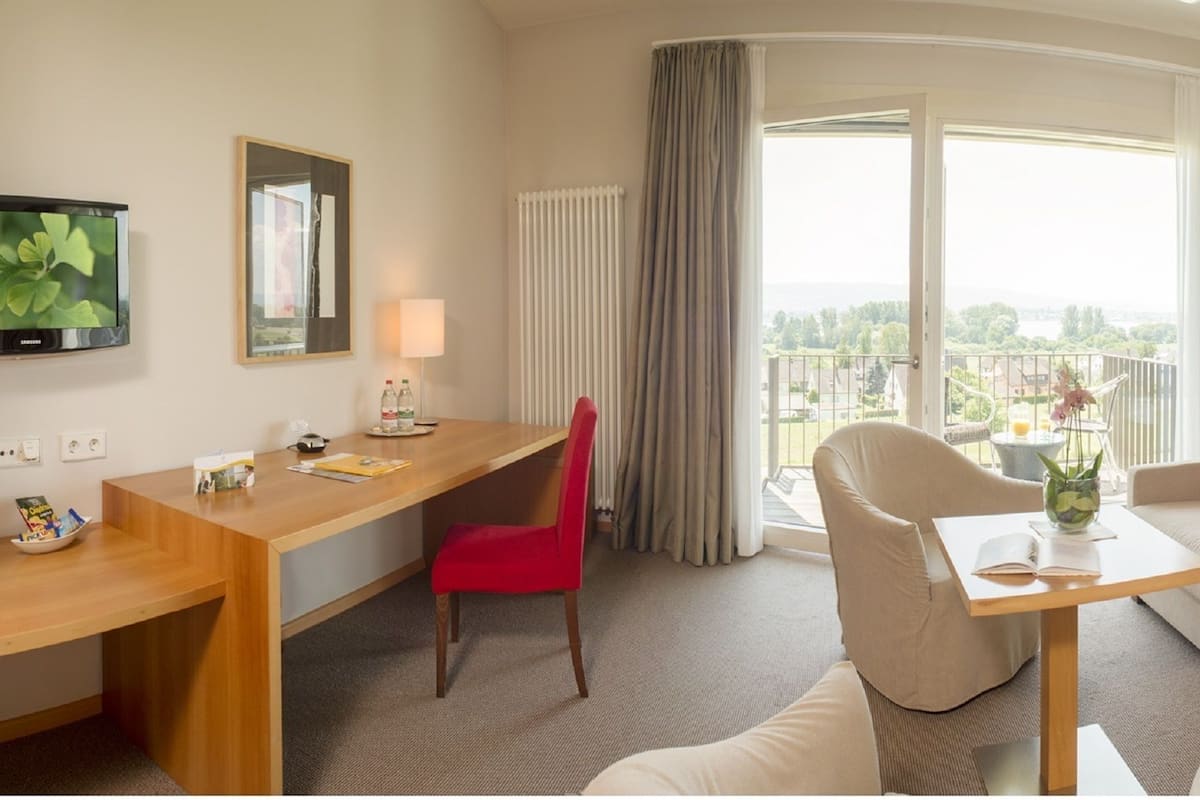 Une chambre d’hôtel comprenant un lit, un canapé, un bureau, une chaise, une télévision et un balcon avec vue.