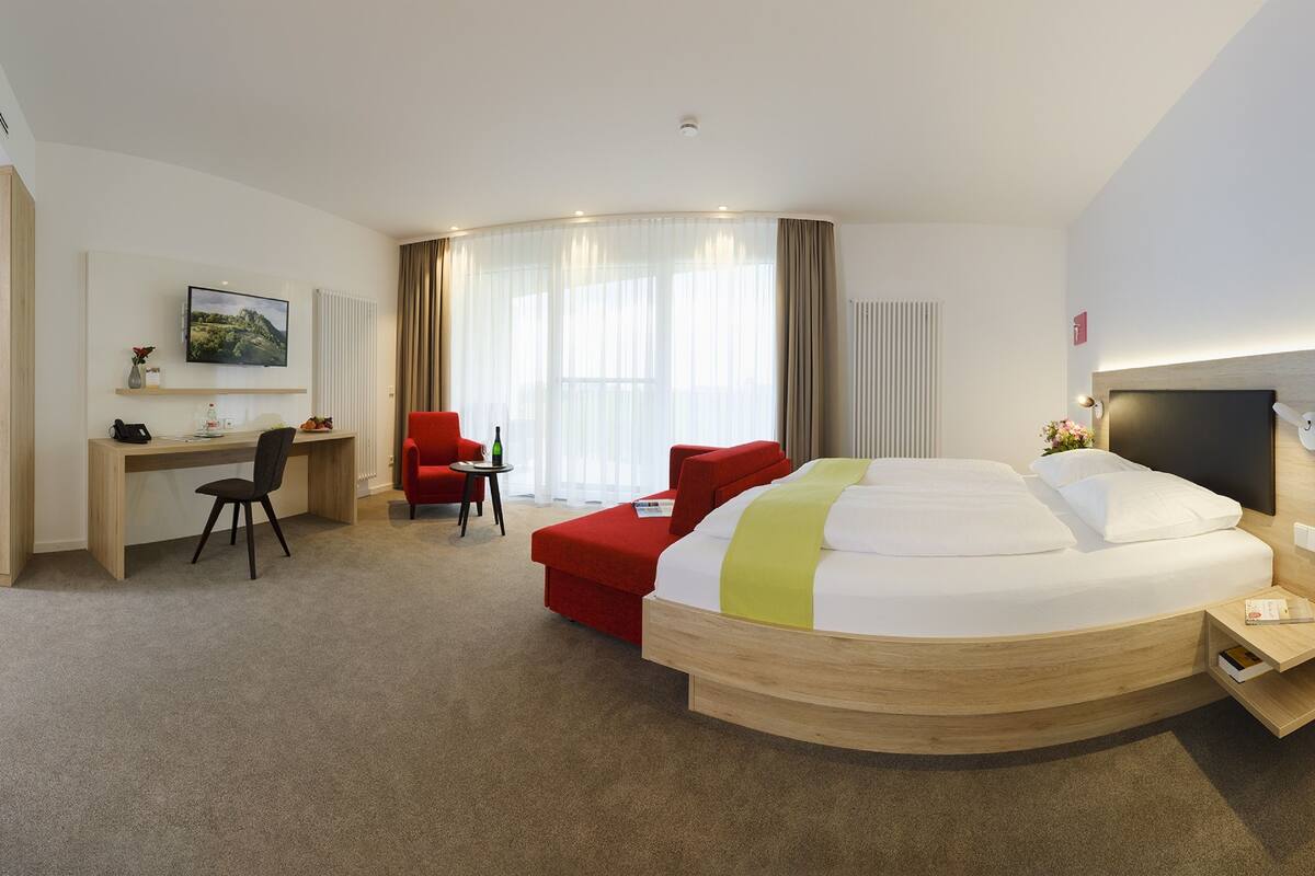 Une chambre d’hôtel avec un lit, un bureau, une chaise et un téléviseur.