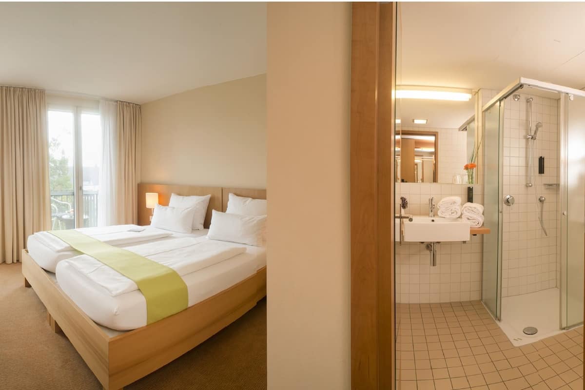 Une chambre d’hôtel comprenant un lit, un bureau, une chaise et une salle de bain avec douche et lavabo.