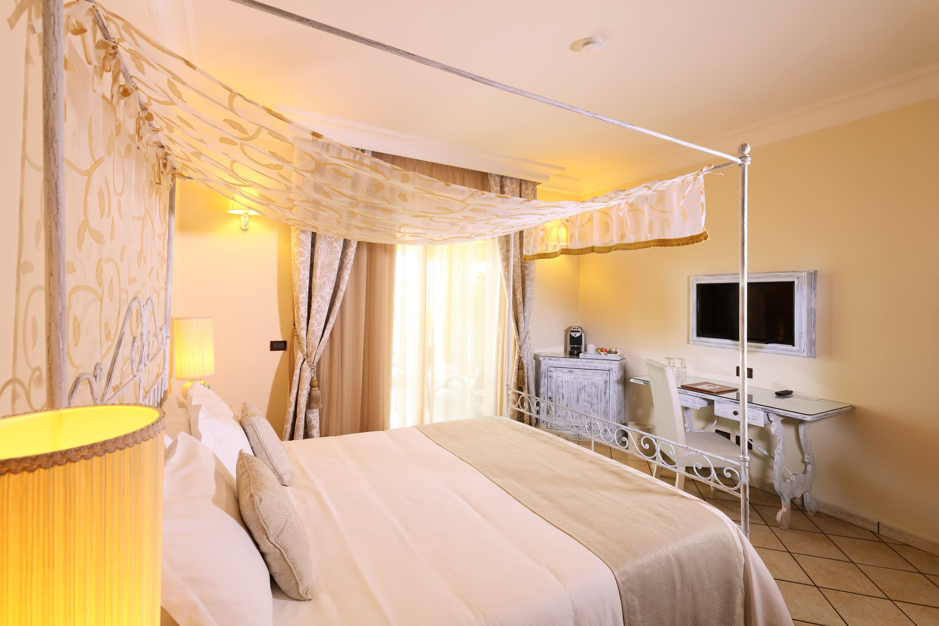 Een hotelkamer met een bed, een bureau, een televisie en een lamp.