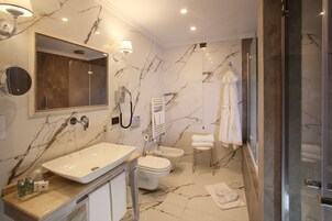 Uma casa de banho moderna com uma pia grande, sanita, bidé e cabine de duche em vidro.