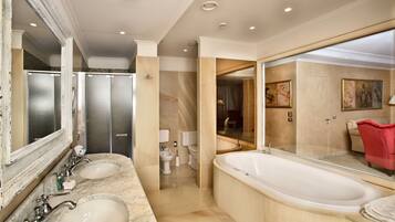 Un bagno ampio con due lavabi in marmo, una grande vasca da bagno freestanding e una zona doccia con pareti in vetro.