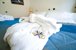 A neatly made bed with a blue bedspread and a white towel with embroidered text placed on it.