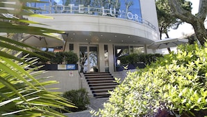 Una entrada moderna de hotel con fachada curva, una escalera que conduce a la entrada y un letrero que dice TELLUXOR.