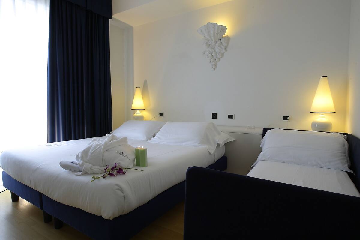 A hotel room with two beds, a wall-mounted light fixture, and a bedside table.
