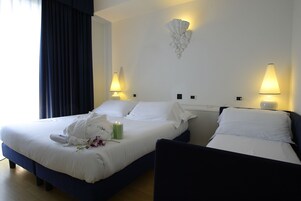 A hotel room with two beds, a wall-mounted light fixture, and a bedside table.