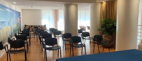 Ett konferensrum med rader av stolar, ett bord och ett stort fönster.