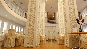 Une salle de conférence dotée d’un plafond haut, d’une table centrale et de rangées de chaises.