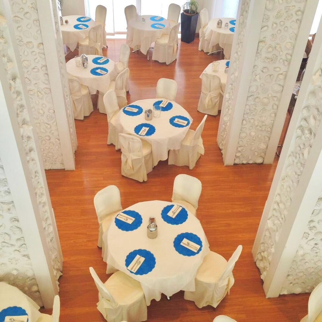 A conference room with round tables, white chairs, and blue placemats.
