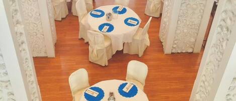 A conference room with round tables, white chairs, and blue placemats.
