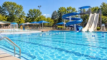 A swimming pool with a water slide and lounge chairs.