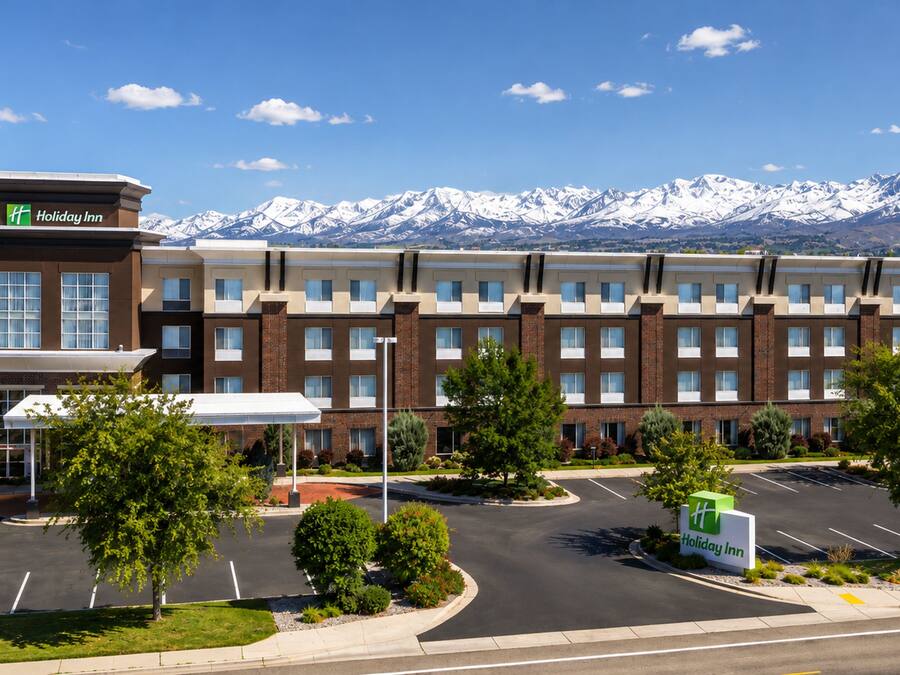 A Holiday Inn hotel with a parking lot and a mountain backdrop.