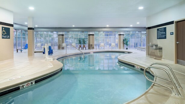 An indoor swimming pool with clear water, a pool lift, and a view of the outside through large windows. - Holiday Inn Boise Airport by IHG (Boise)