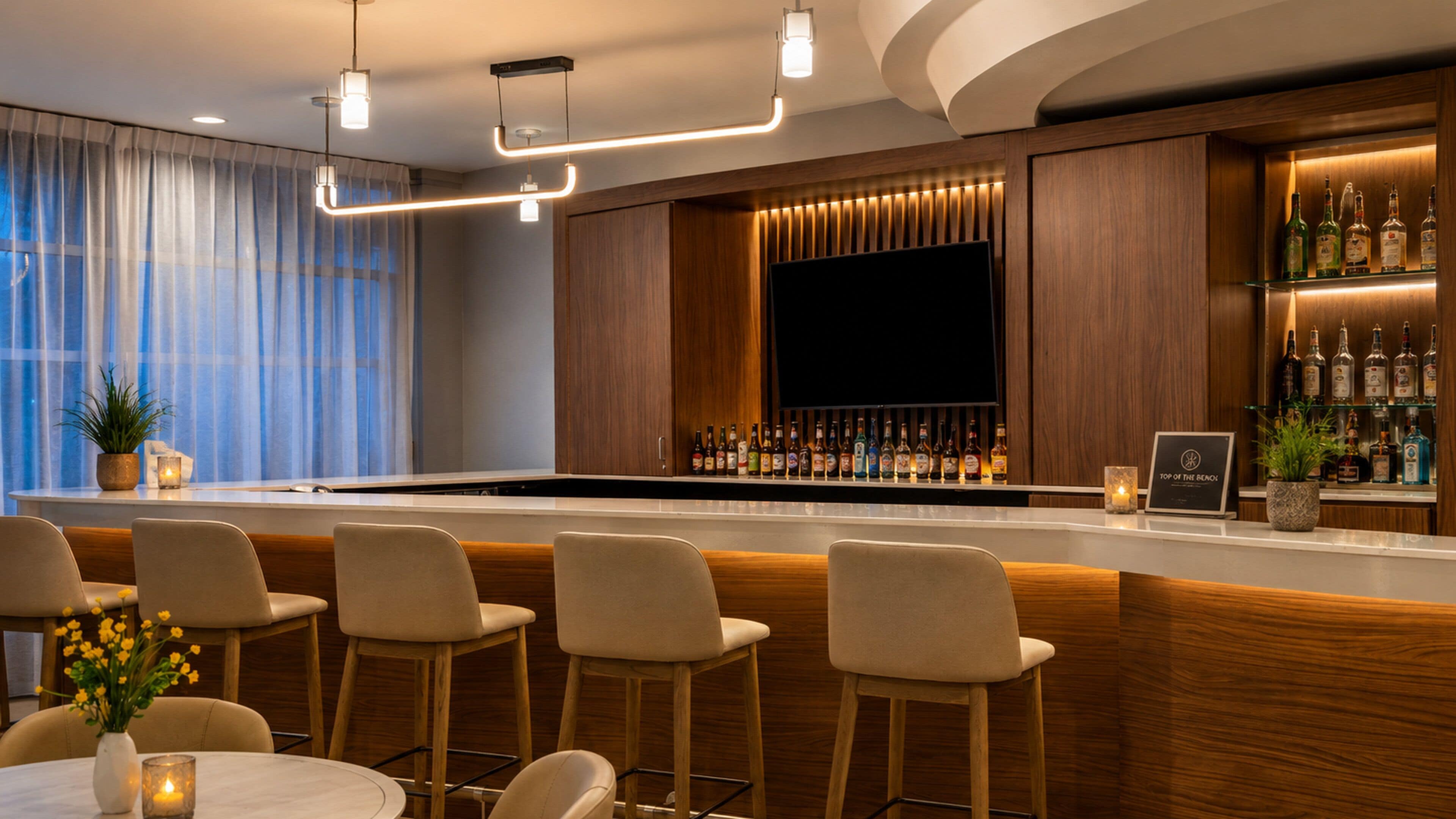A bar area with wooden bar counter, multiple seating options, and a television screen.