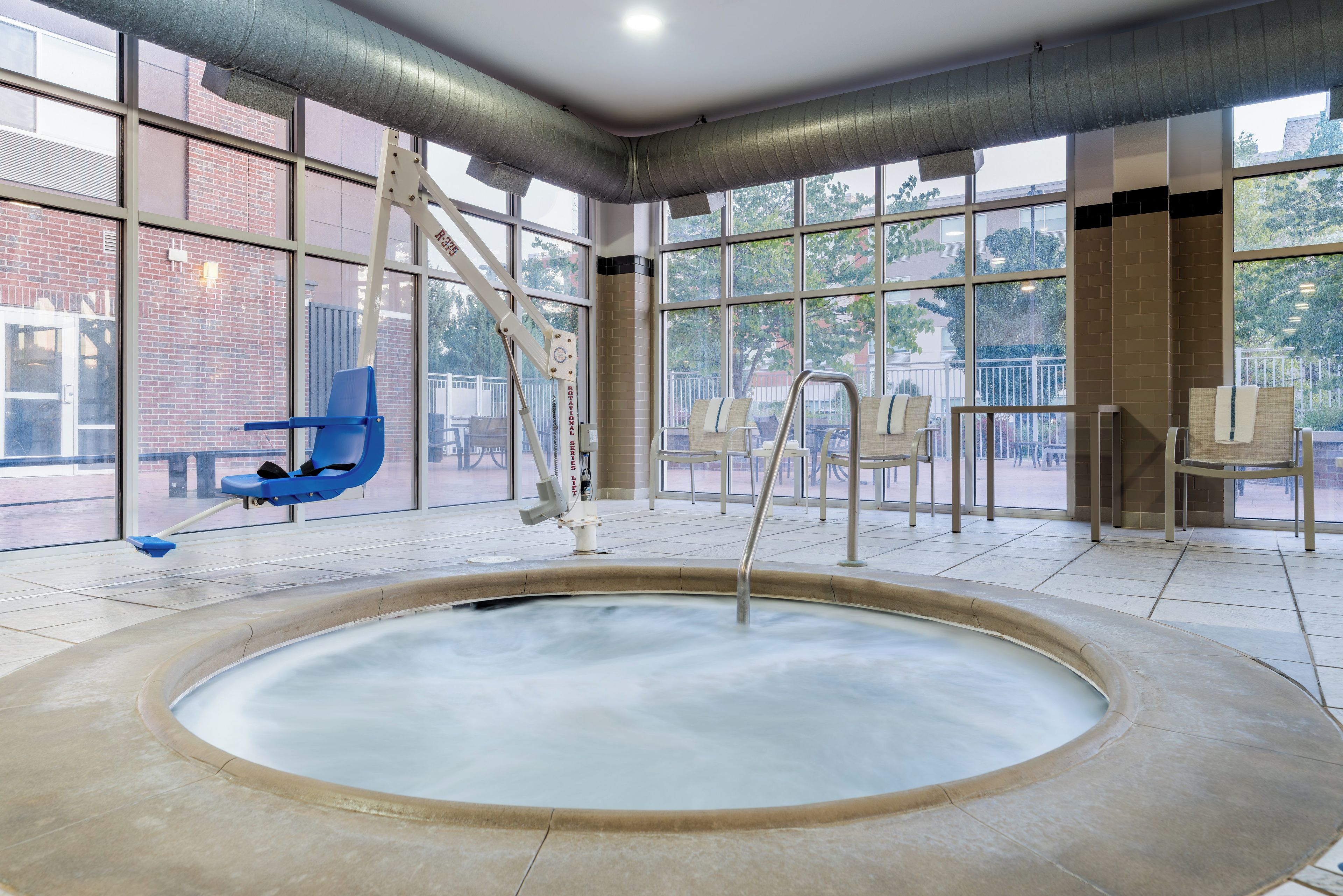 A large indoor hot tub with a view of the outside through large windows.