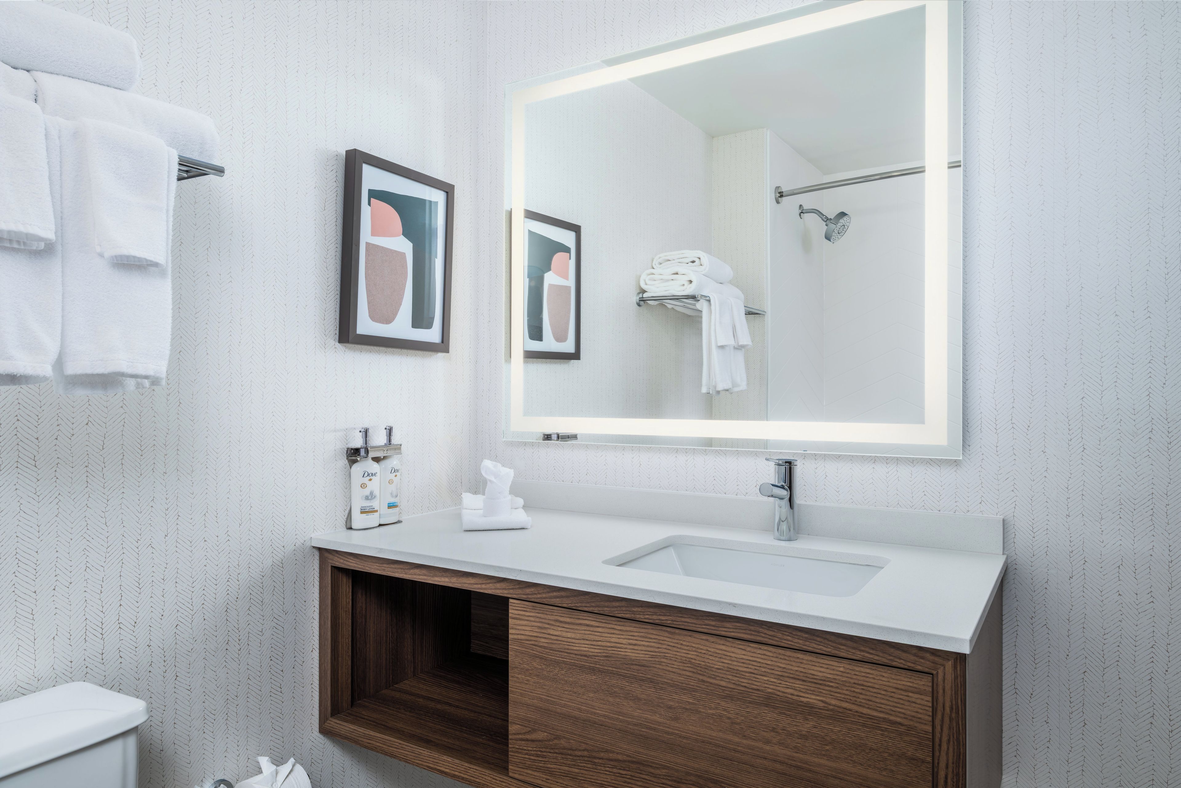 Une salle de bain moderne avec un lavabo blanc, un meuble-lavabo en bois et un grand miroir.