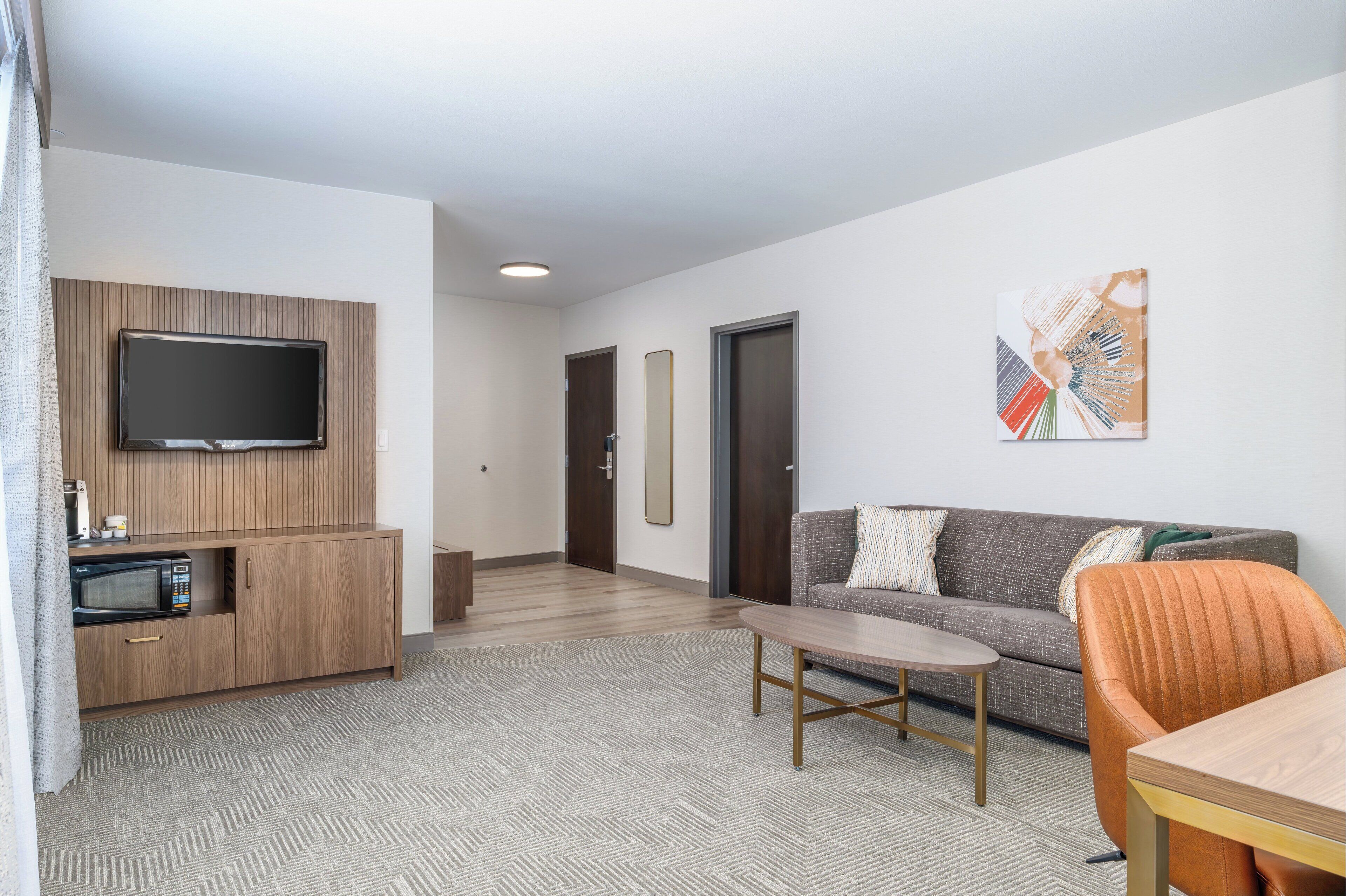 A modern living room with a flat-screen TV, wooden cabinet, sofa, and a coffee table.