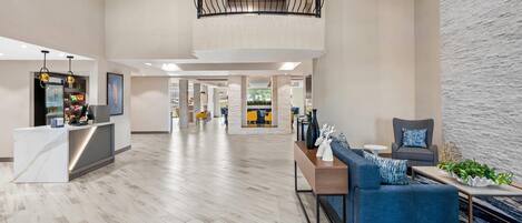 A spacious lobby with a reception desk, seating area, and a staircase.