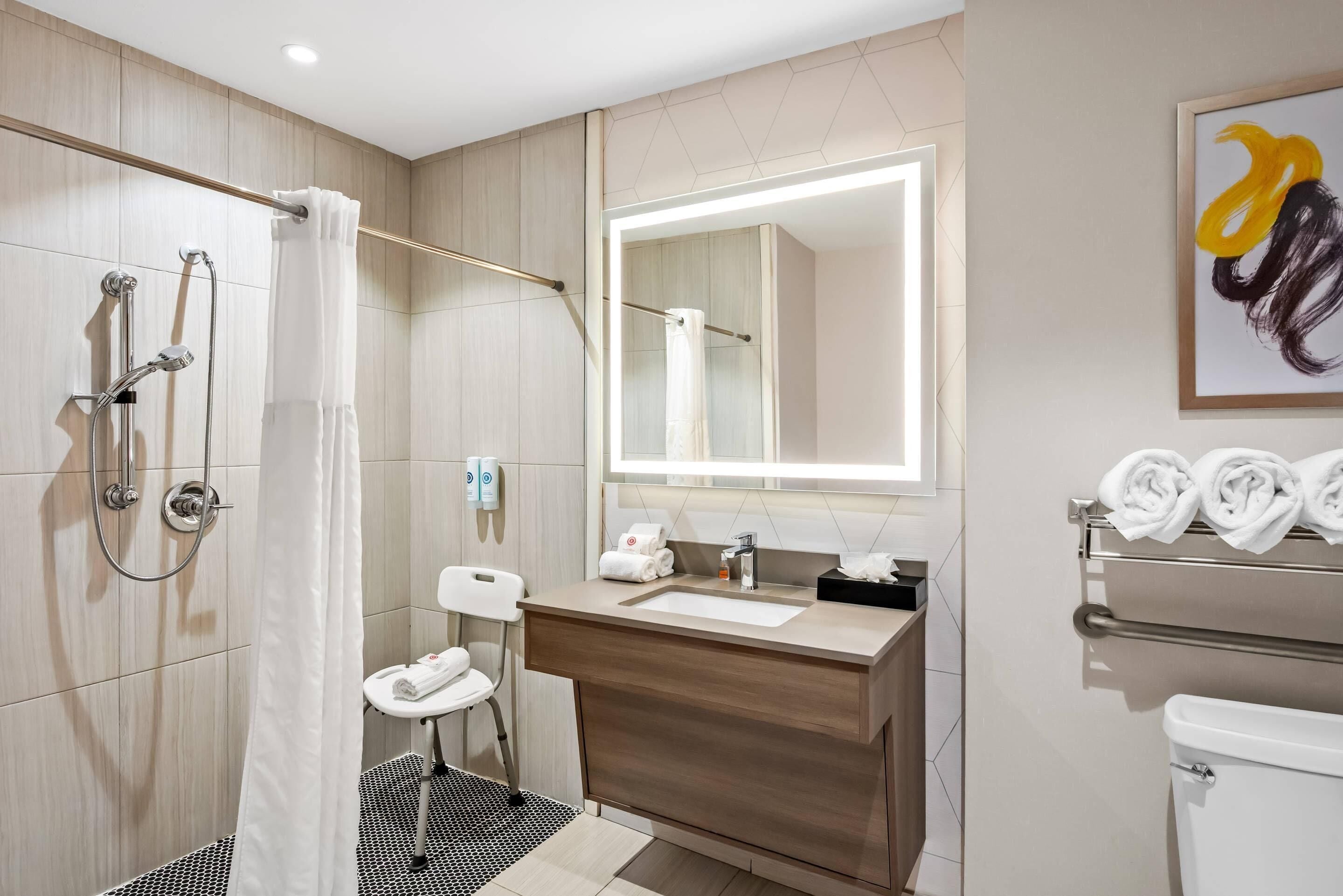 Un baño moderno con ducha, inodoro, lavamanos y toallero.
