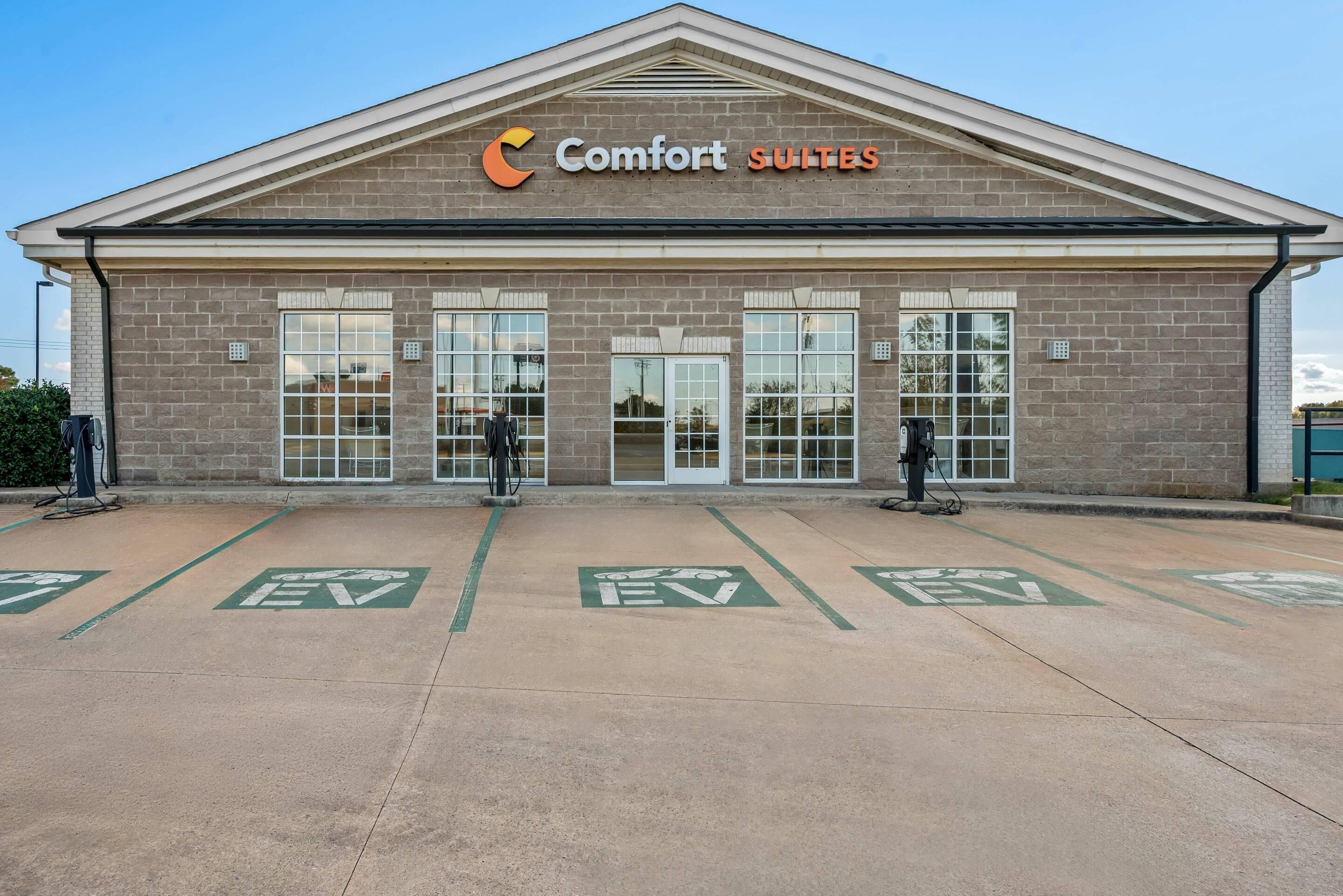 A building with the sign "Comfort Suites" and EV charging spots in front.