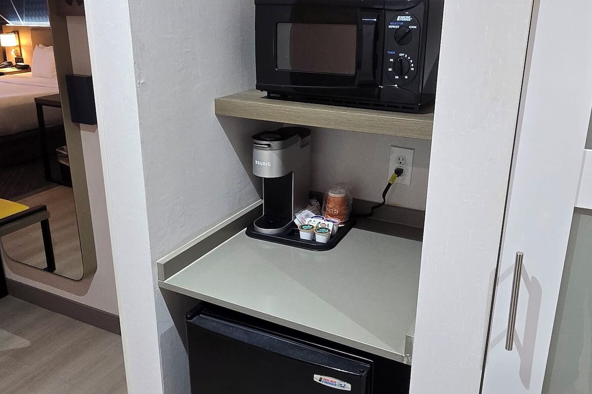 A compact kitchenette with a microwave, coffee maker, and a small refrigerator.