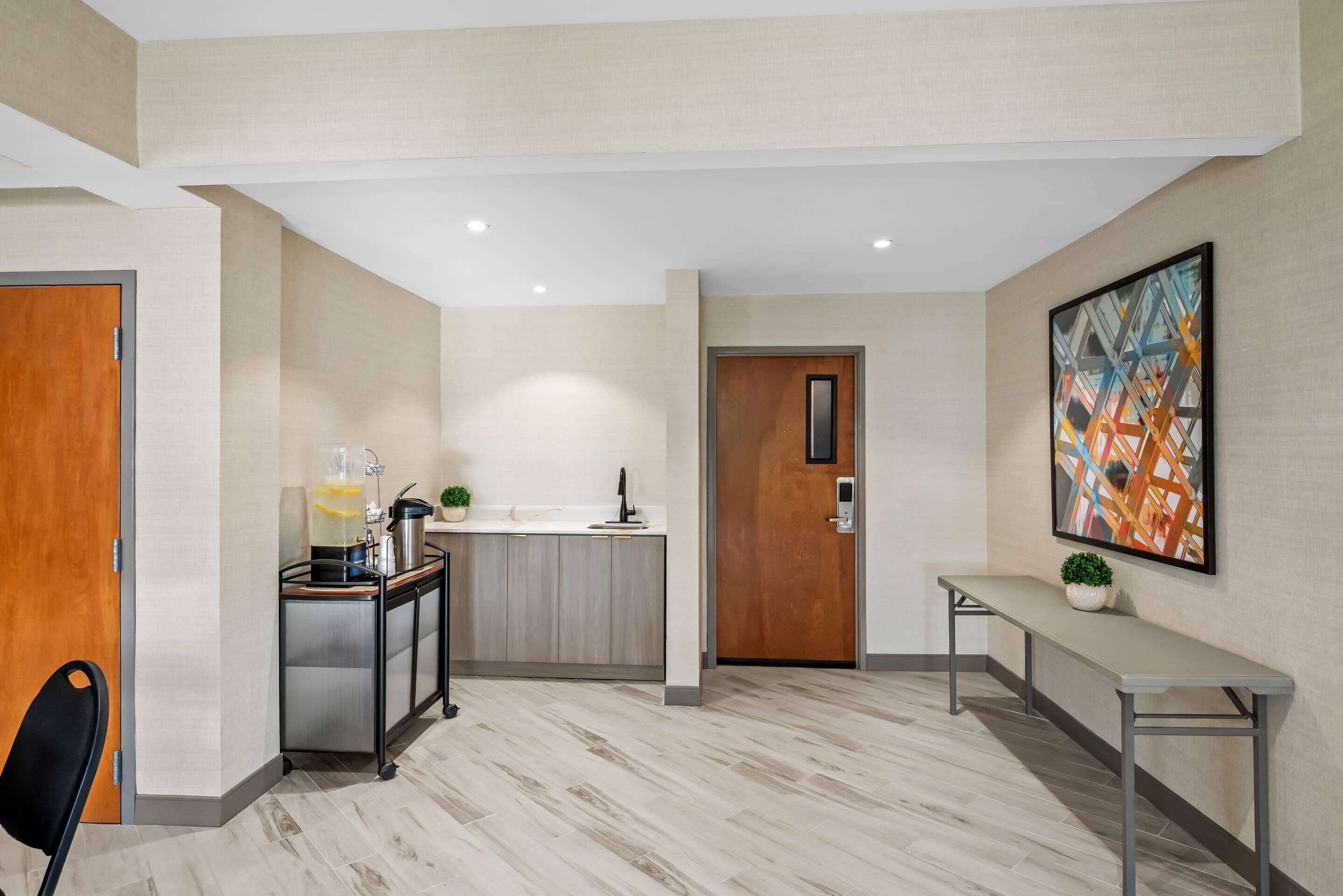 A modern hotel lobby with a kitchen area, a bench, and a door.