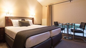 A hotel room with a large bed, a desk, and a balcony with chairs. - Turnhout City Hotel (Turnhout)