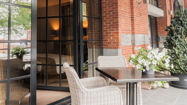 A patio area with wicker furniture, a table, and a potted plant. - Turnhout City Hotel (Turnhout)