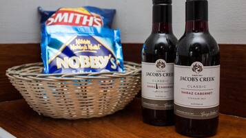 Dos botellas de Jacob's Creek Classic Shiraz Cabernet y una cesta con una bolsa de chips Smith's Nobby's.