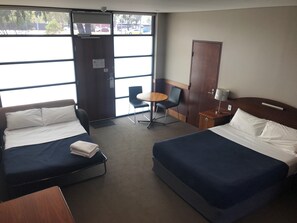 A hotel room with two beds, a desk, a chair, and a small table. - Highlander Hotel (Gilles Plains)