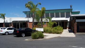 A building with a green roof, a gaming room, and an entertainment area. There are cars parked in front.