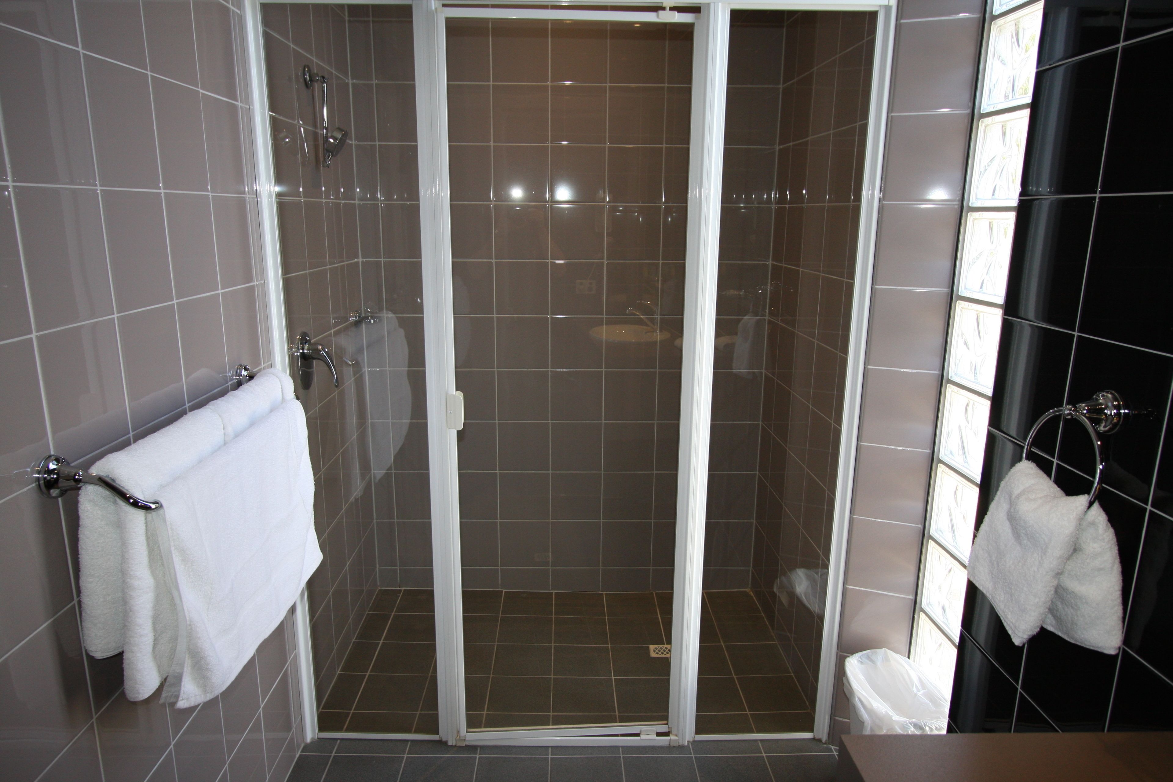 A shower area with a glass door, tiled walls, and a white towel hanging on the wall.