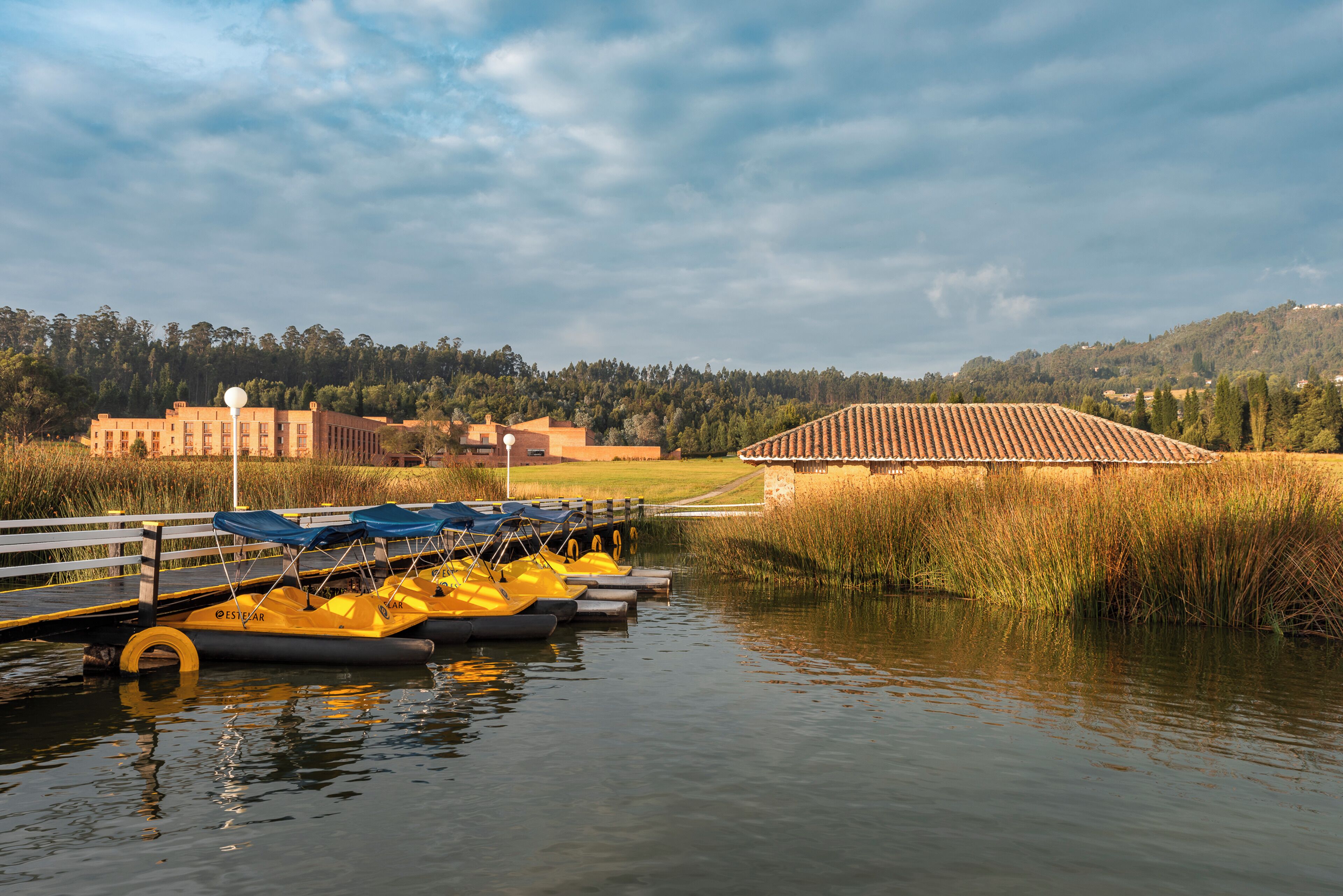 A calm water body with a dock, yellow boats, and a building in the background.