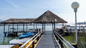 A pier with a thatched-roof structure, a boat docked, and a water taxi.