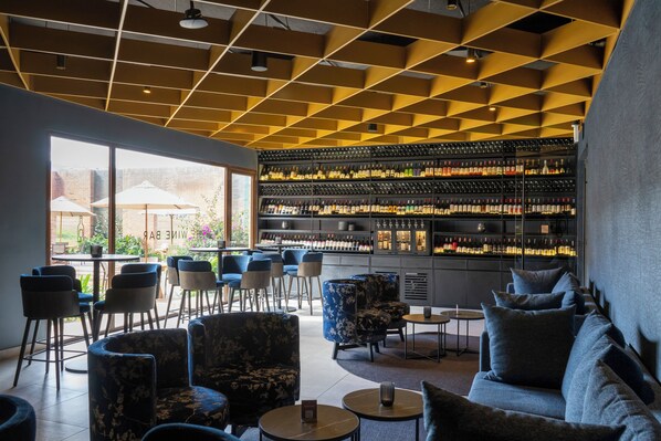A bar area with a wine rack, seating, and a view of the outside.